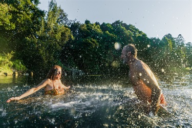A couple enjoy a playful moment together in the refreshing waters of the Bellinger River