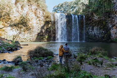 A couple stand admiring the cascading water at Dangar Falls, Dorrigo